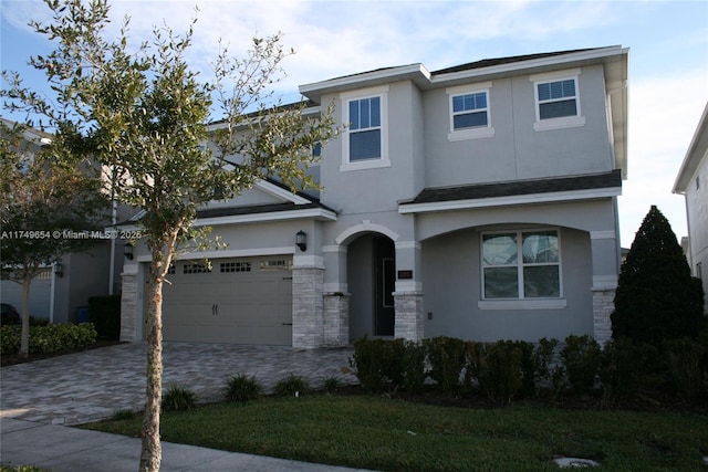 view of front of property with decorative driveway, an attached garage, and stucco siding