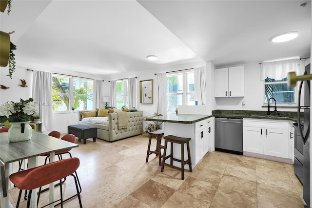 kitchen with open floor plan, white cabinetry, dishwasher, and a peninsula