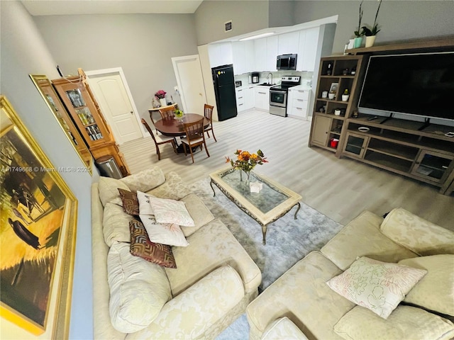 living room with visible vents, high vaulted ceiling, and wood finished floors