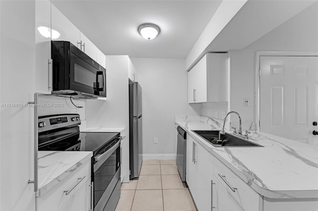 kitchen featuring appliances with stainless steel finishes, white cabinets, a sink, and light stone countertops