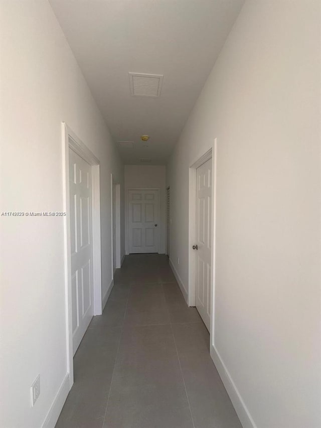 hall with baseboards, visible vents, and tile patterned flooring