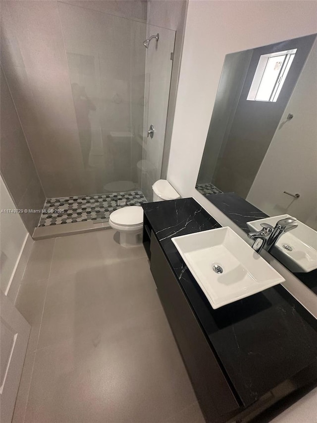 full bathroom featuring tile patterned flooring, tiled shower, vanity, and toilet