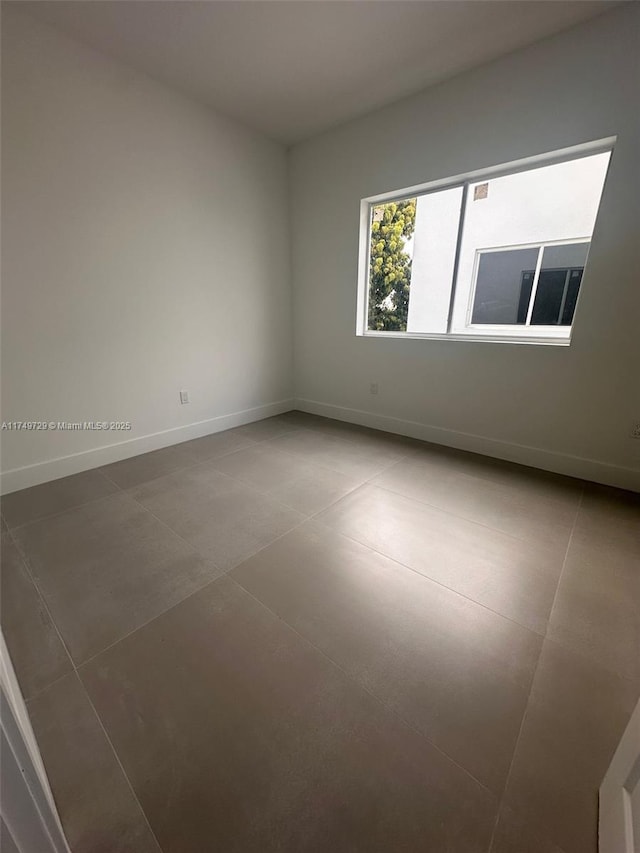 empty room featuring tile patterned floors and baseboards