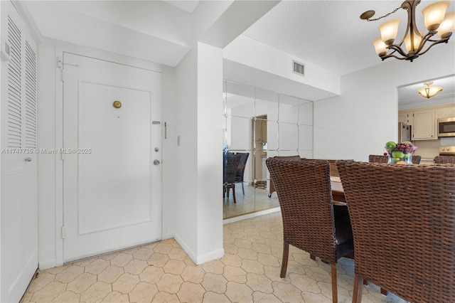 dining area with visible vents, a notable chandelier, a textured ceiling, and baseboards