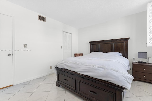 bedroom featuring light tile patterned floors, baseboards, visible vents, and a closet