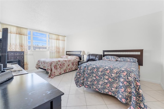 bedroom with light tile patterned flooring, a textured ceiling, and baseboards