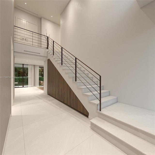 staircase featuring a high ceiling and tile patterned floors