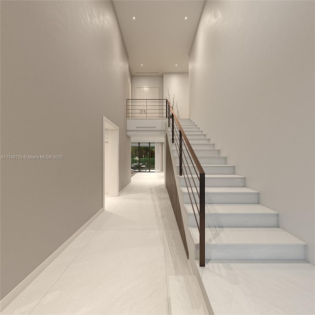 stairs featuring baseboards, a high ceiling, and recessed lighting