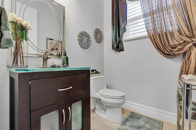 half bath with toilet, tile patterned flooring, baseboards, and vanity