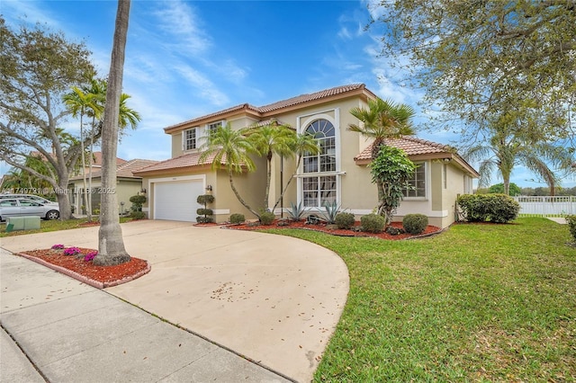 mediterranean / spanish house featuring fence, a tile roof, driveway, stucco siding, and a front yard