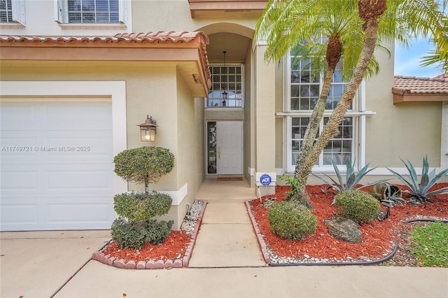 property entrance featuring a tiled roof, an attached garage, and stucco siding