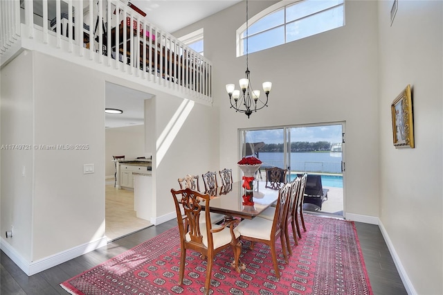 dining area featuring baseboards, a high ceiling, a chandelier, and dark wood finished floors