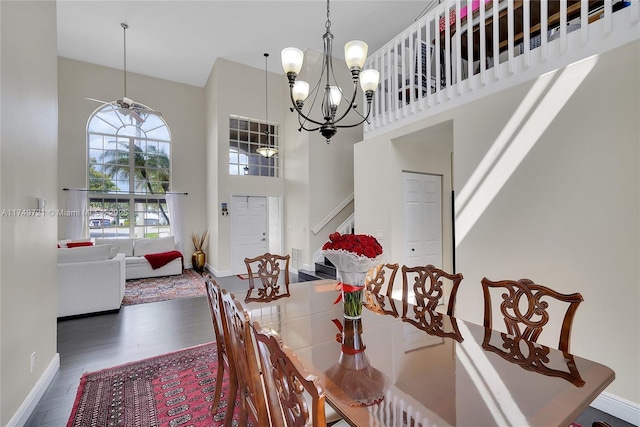 dining room featuring a towering ceiling, baseboards, stairway, and dark wood-type flooring