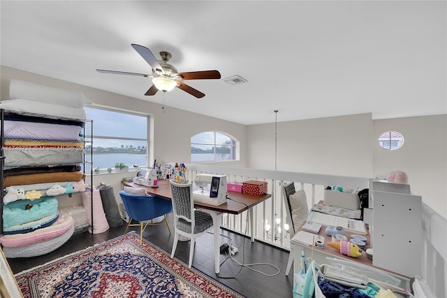 office space featuring a water view, ceiling fan, visible vents, and wood finished floors