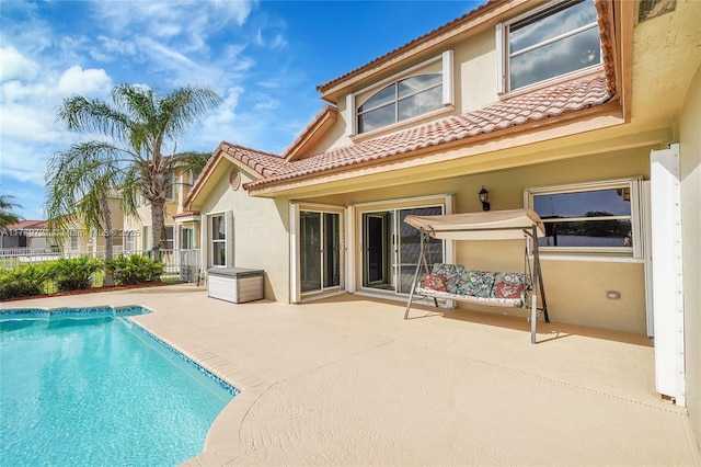 back of house with a fenced in pool, stucco siding, a patio area, fence, and a tiled roof