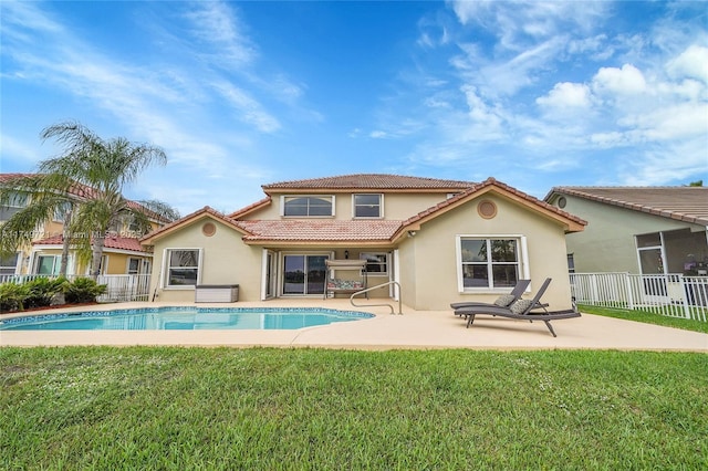 rear view of property featuring a patio, fence, a yard, a fenced in pool, and stucco siding