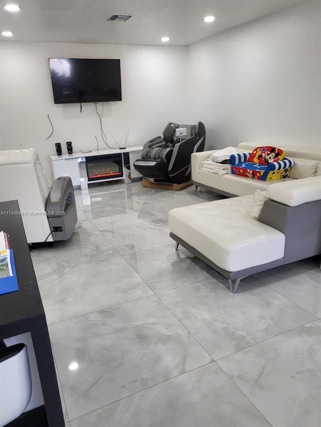 living area with marble finish floor, recessed lighting, visible vents, and a glass covered fireplace