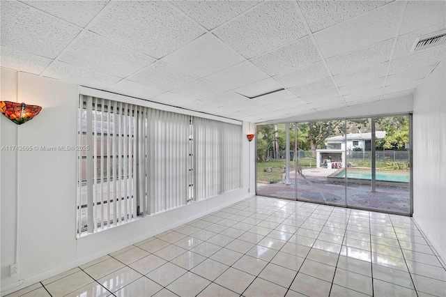 unfurnished room featuring light tile patterned floors, a drop ceiling, and visible vents