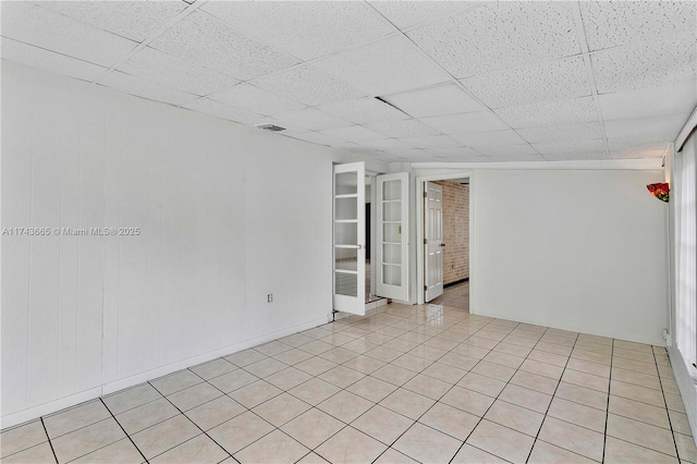 spare room with light tile patterned floors, visible vents, and a drop ceiling