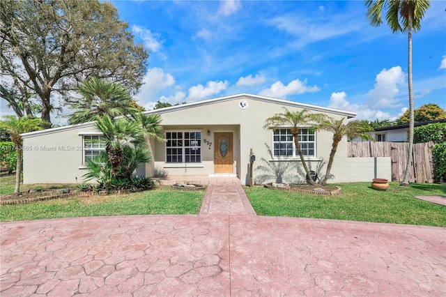 ranch-style home featuring a front yard, fence, and stucco siding