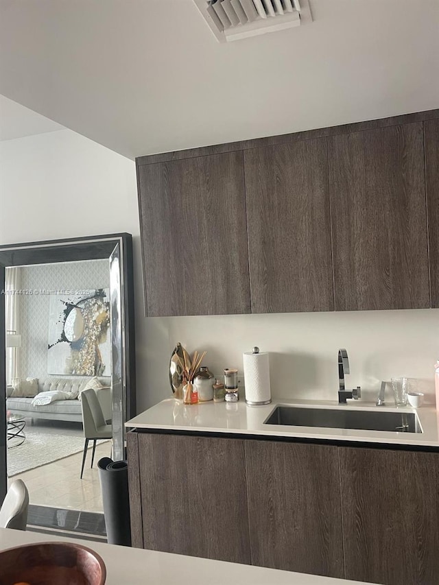 kitchen featuring visible vents, light countertops, a sink, and dark brown cabinetry