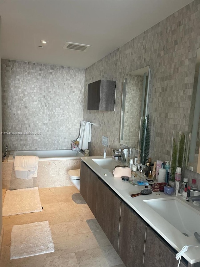 full bathroom featuring a tub with marble appearance, visible vents, a sink, and toilet