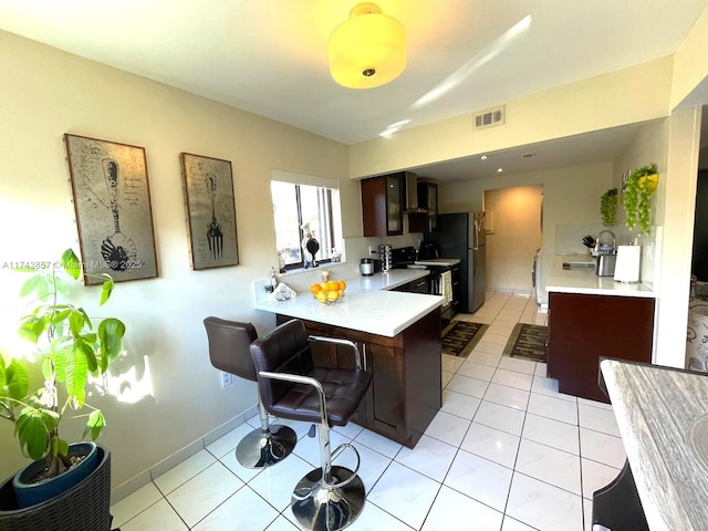 8415 SW 107th Ave Unit 363W, Miami, FL 33173 - kitchen featuring light countertops, freestanding refrigerator, wall chimney exhaust hood, a peninsula, and a breakfast bar