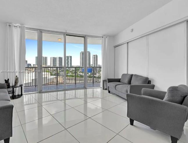 living room featuring light tile patterned floors, floor to ceiling windows, and a city view