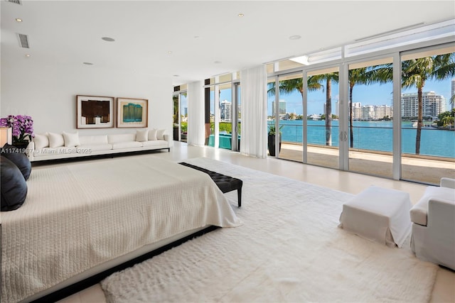 bedroom featuring access to exterior, a view of city, floor to ceiling windows, recessed lighting, and a water view