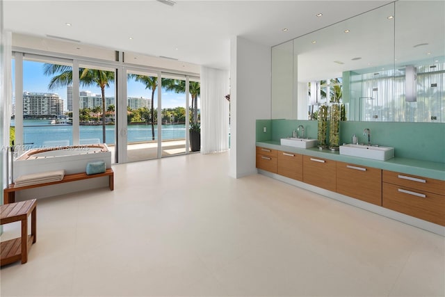 full bathroom with a freestanding tub, a water view, a sink, and double vanity