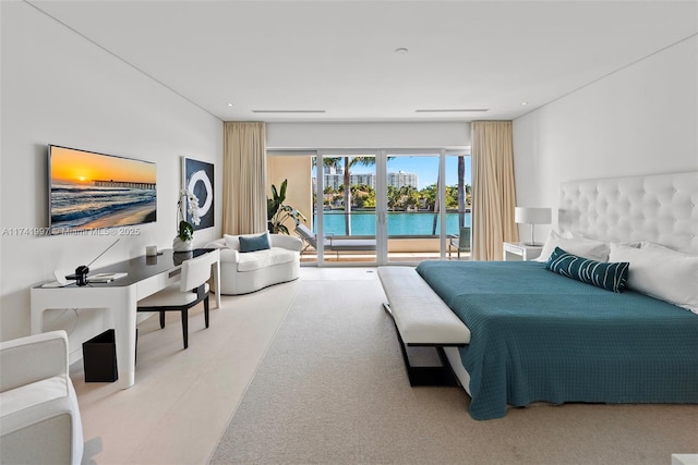 bedroom featuring access to exterior, recessed lighting, and a water view