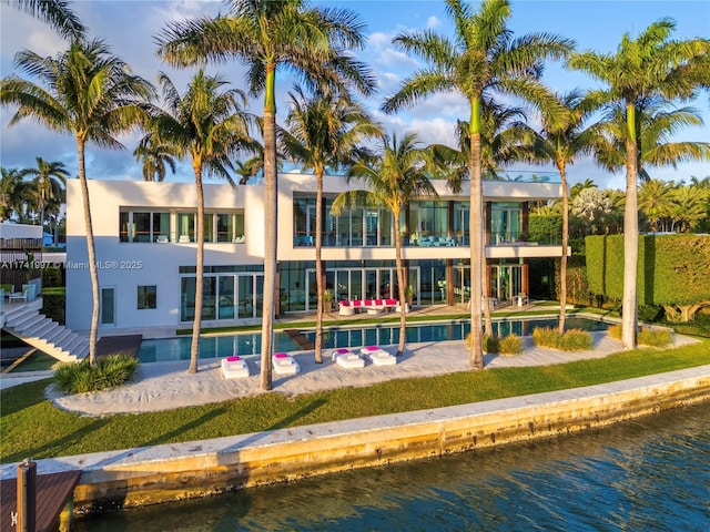 back of house featuring a water view and an outdoor pool