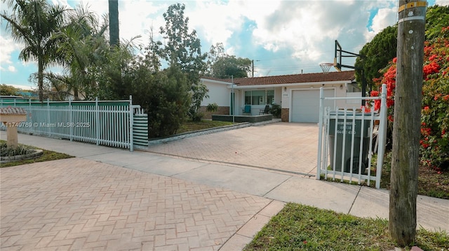 view of front facade featuring an attached garage, a fenced front yard, decorative driveway, and stucco siding