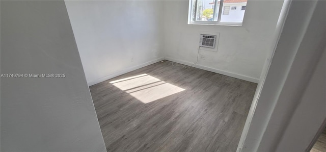 spare room with a wall mounted air conditioner, wood finished floors, and baseboards