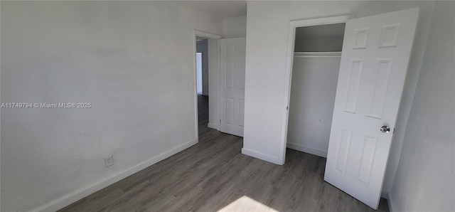 unfurnished bedroom featuring a closet, baseboards, and wood finished floors