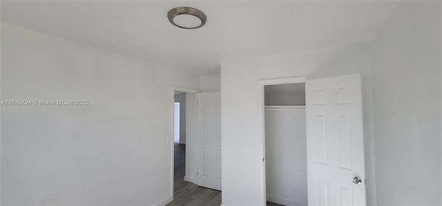 unfurnished bedroom featuring a closet, baseboards, and wood finished floors