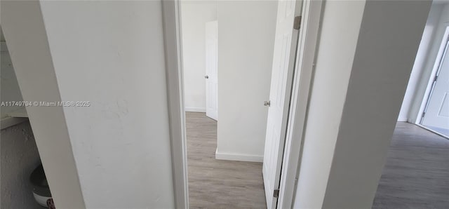 hall featuring light wood finished floors and baseboards