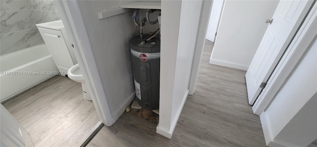 interior space featuring washer / dryer, baseboards, wood finished floors, and electric water heater