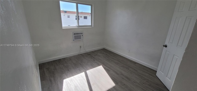 empty room with dark wood-style floors, baseboards, and a wall mounted air conditioner