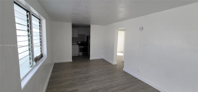 unfurnished room featuring baseboards and dark wood-style flooring