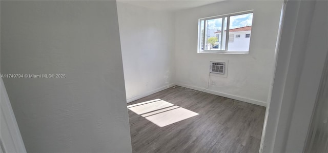 spare room featuring baseboards, wood finished floors, and a wall mounted AC