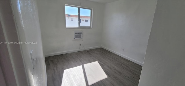 empty room with dark wood-style floors, a wall mounted air conditioner, and baseboards