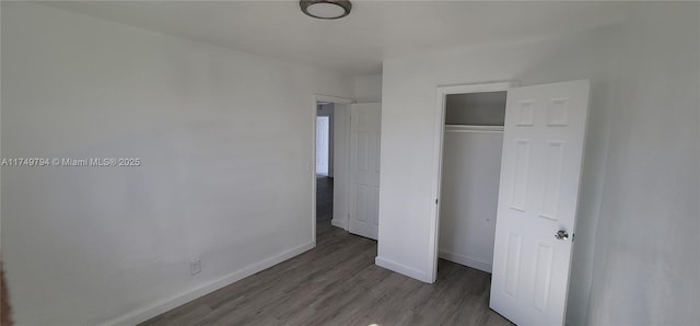 unfurnished bedroom featuring a closet, wood finished floors, and baseboards