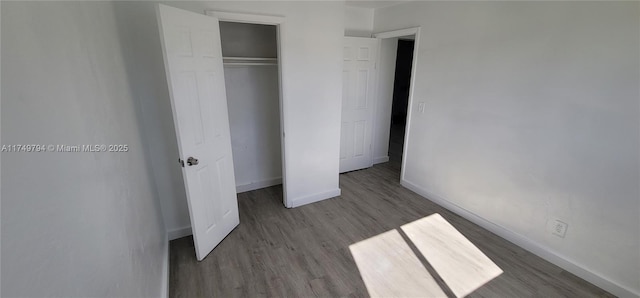 unfurnished bedroom with a closet, wood finished floors, and baseboards