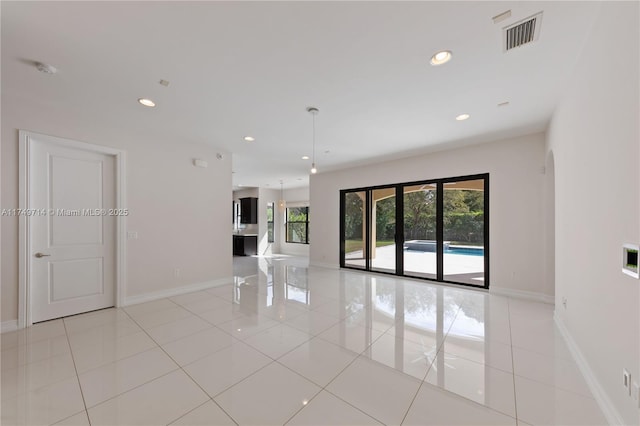 spare room with light tile patterned floors, baseboards, visible vents, arched walkways, and recessed lighting