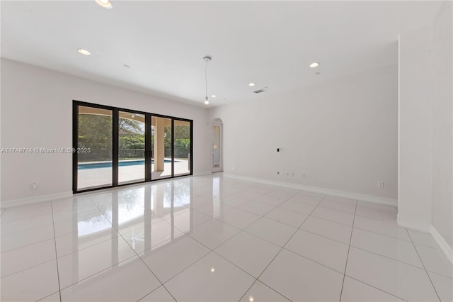 unfurnished room with light tile patterned floors, baseboards, arched walkways, and recessed lighting