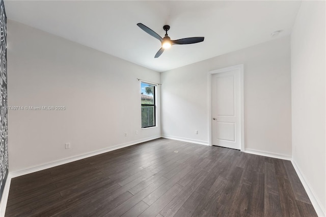 unfurnished room with a ceiling fan, baseboards, and dark wood-type flooring