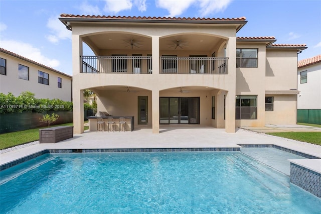 rear view of house with outdoor dry bar, a patio, a ceiling fan, and stucco siding