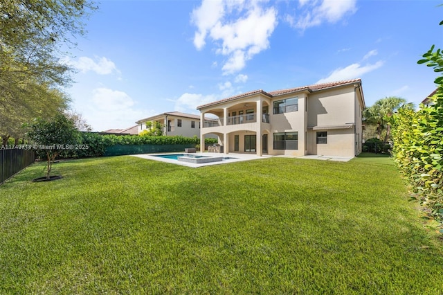 back of house with a fenced backyard, a jacuzzi, a balcony, a yard, and stucco siding