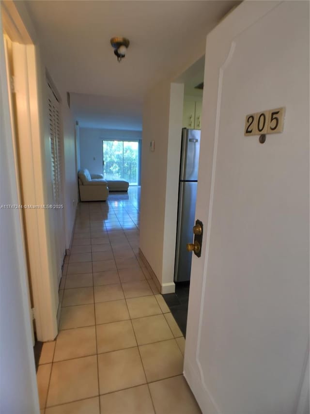 corridor featuring light tile patterned floors and baseboards